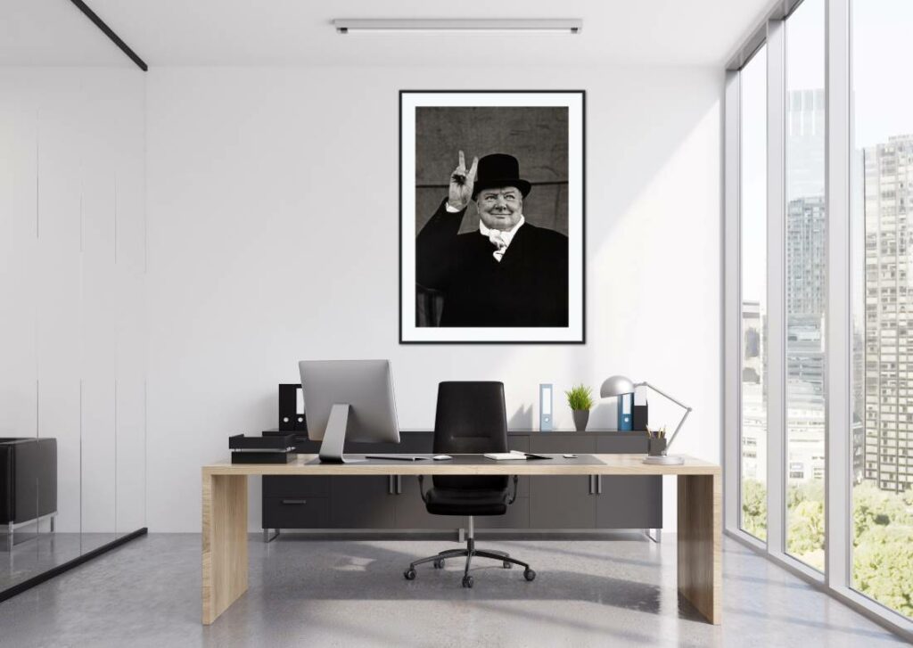 A black and white framed Winston Churchill hanging on a wall behind an office desk