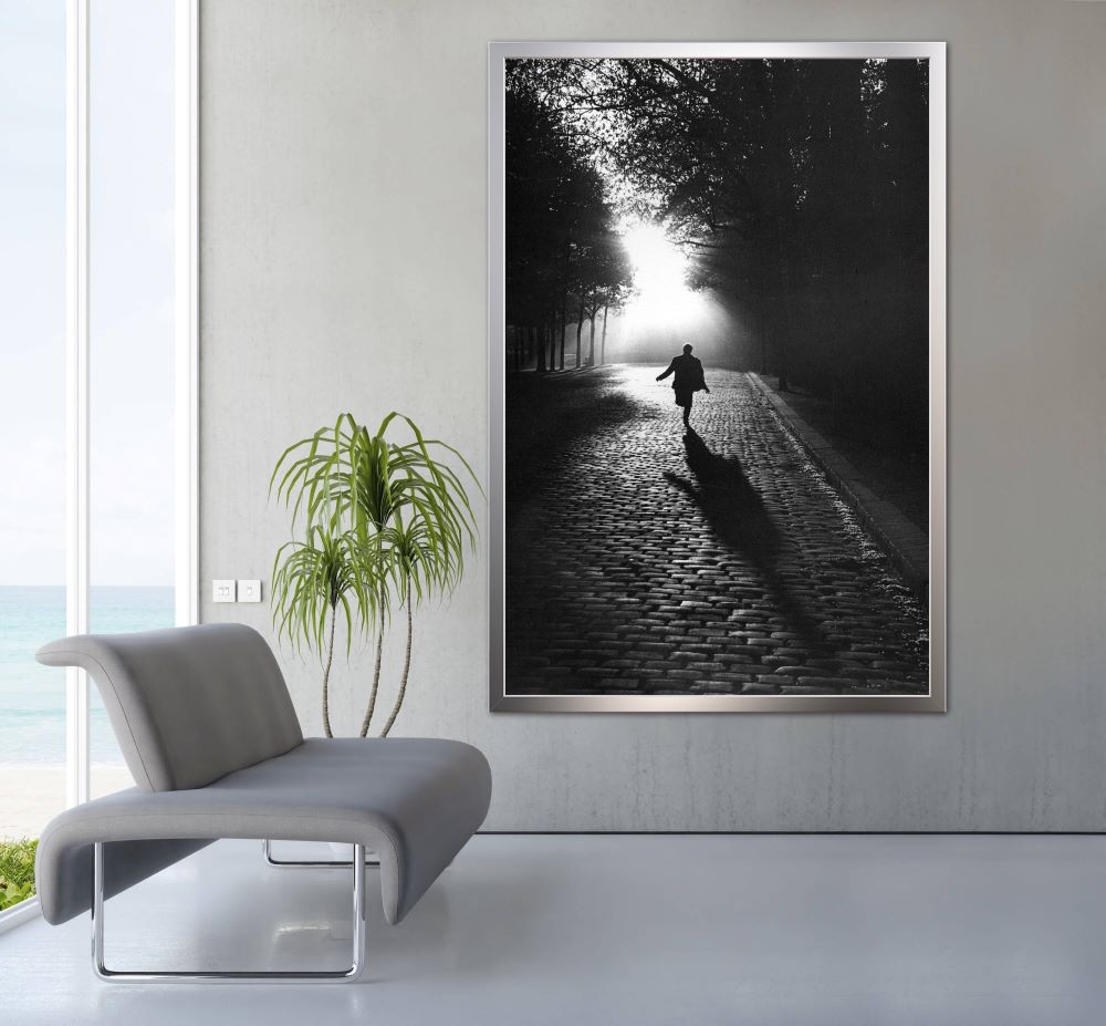 Black and white image of a man running through a cobbled street into the the light