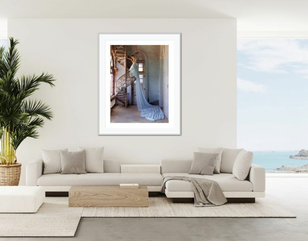 Women on a staircase wearing a blue gown with a very long train hanging over the staircase railing