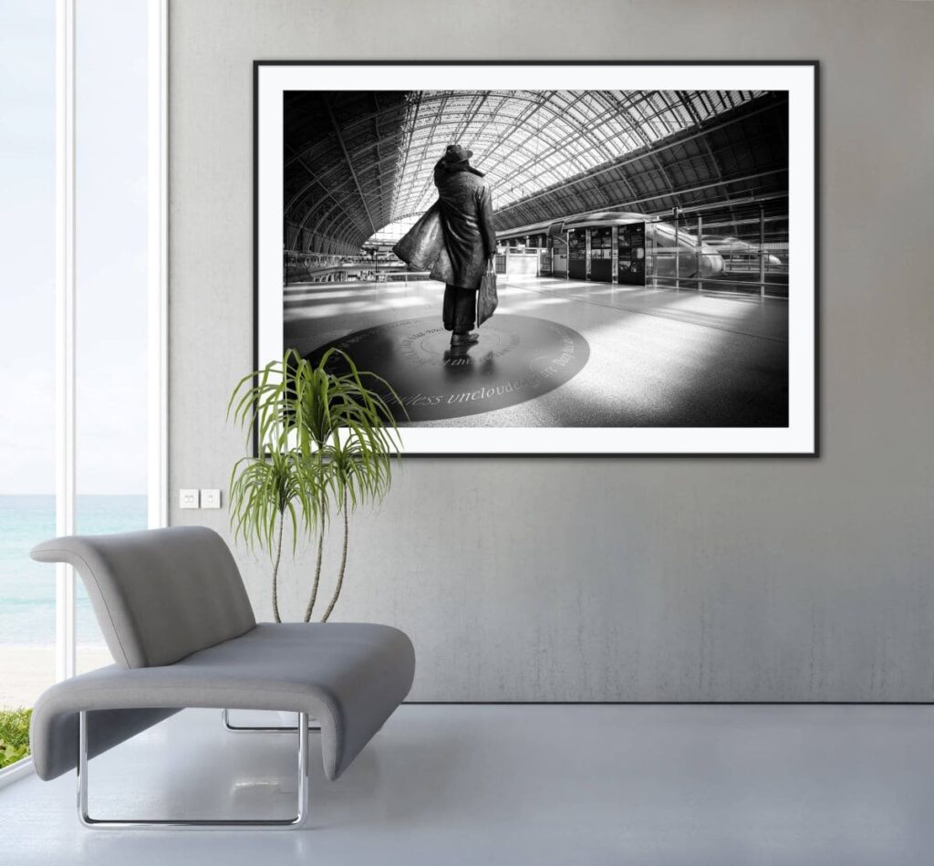 Framed black and white photo of the statue of Sir John Betjeman at the St Pancreas station. The picture is hanging on a wall in a lounge.