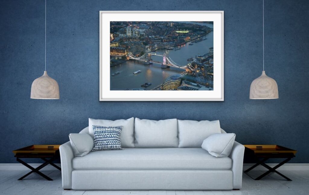 A framed image of an aerial view of Tower Bridge on a wall above a sofa