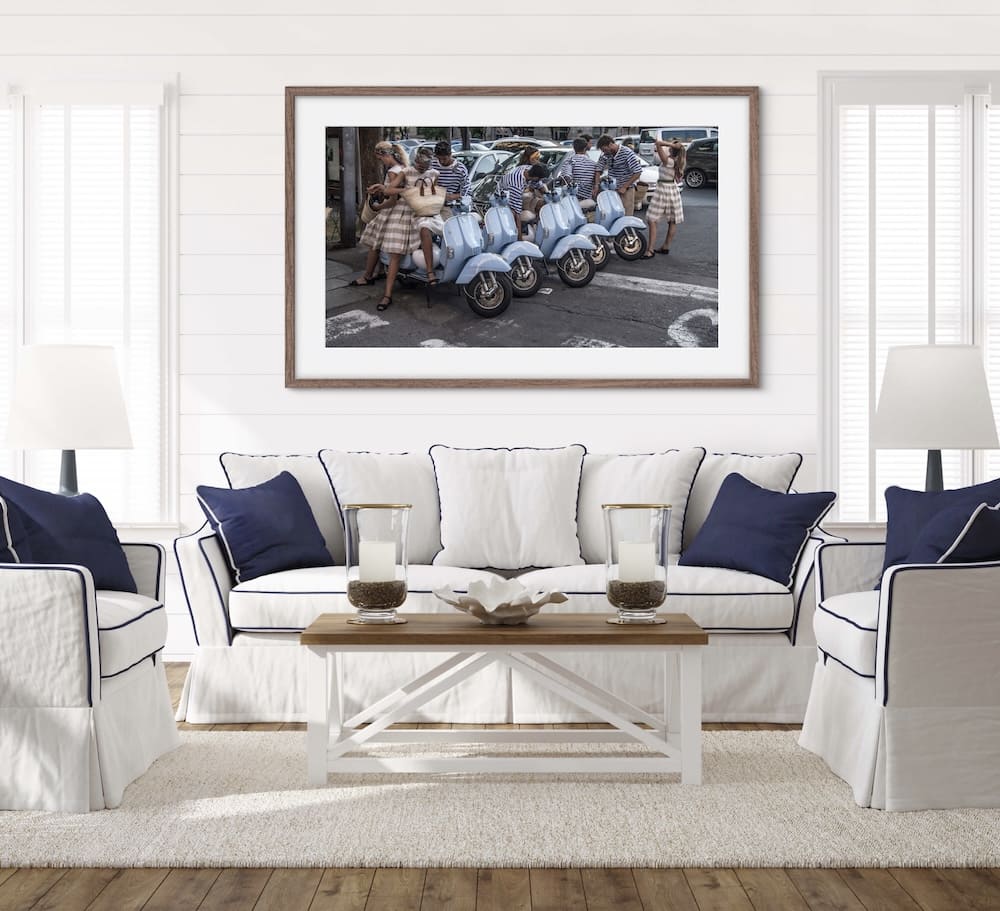 Framed picture of blue parked Vespas with couples dressed the same sitting and standing next to the Vespas